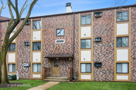 Front view of a brick apartment building with multiple windows and a central entrance.