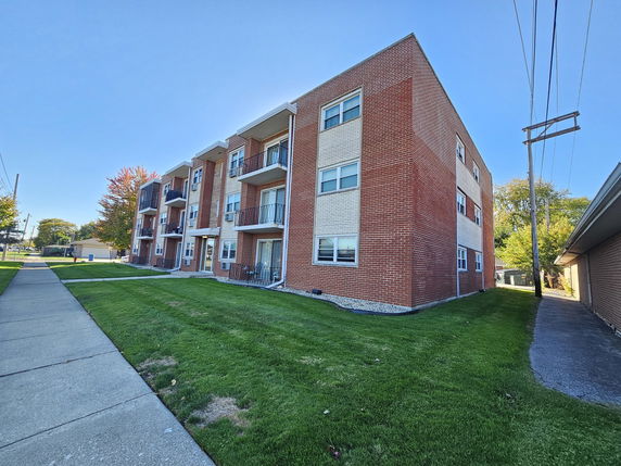 Front view of a three-story apartment building with red brick exterior.