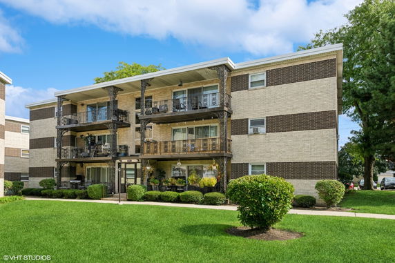 Front view of a three-story apartment building with balconies and brick exterior.