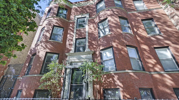 Front view of a multi-story brick building with large windows.