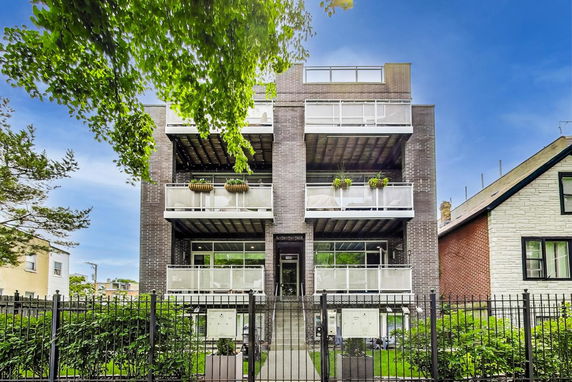 Front view of a modern multi-story building with balconies and brick exterior.