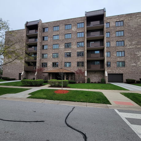 Front view of a multi-story residential building with brick exterior and balconies.