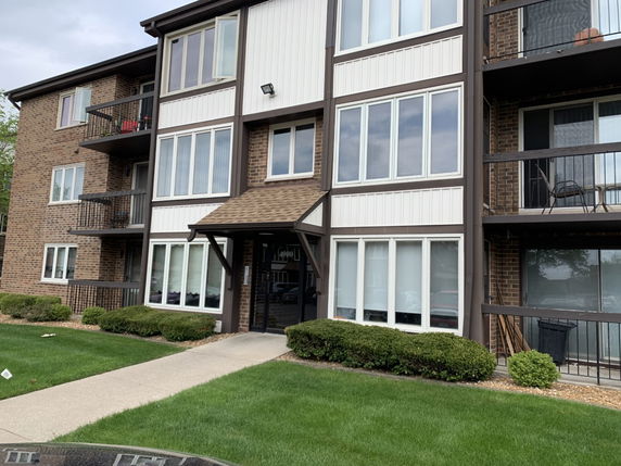 Front view of a multi-story apartment building with brick exterior and balconies.
