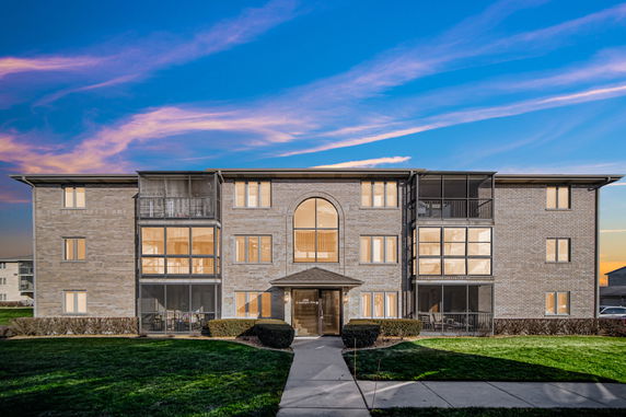 Front view of a three-story apartment building with large windows and a central entrance.
