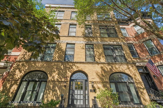 Front view of a multi-story brick building with large windows and a central arched doorway.