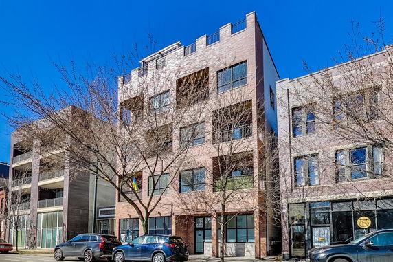 Front view of a multi-story brick building with large windows and balconies.