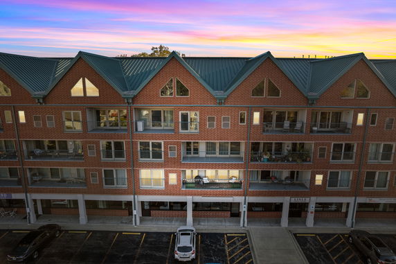 Front view of a multi-story residential building with balconies and a green roof.