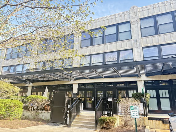 Front view of a multi-story building with large windows and metal awnings.