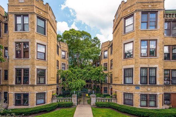 Front view of a brick apartment building with multiple stories and large windows.