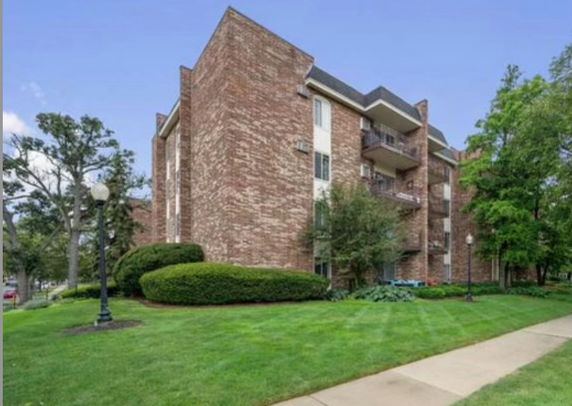 Front view of a multi-story brick apartment building with balconies.