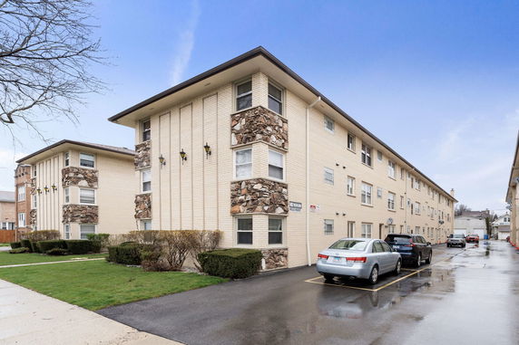 Front view of a multi-story apartment building with brick and stone exterior.