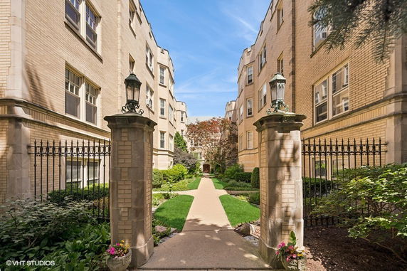 Front view of a multi-story building with a pathway and garden entrance.