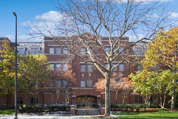 Front view of a multi-story brick building with surrounding trees.
