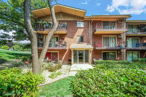 Front view of a three-story brick apartment building with balconies.