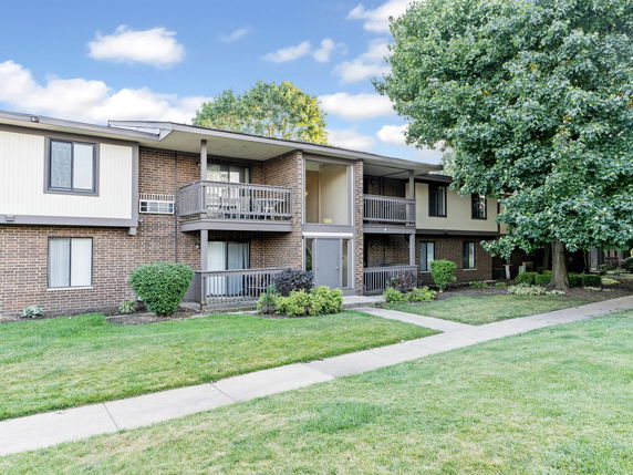 Front view of a two-story brick apartment building with balconies.