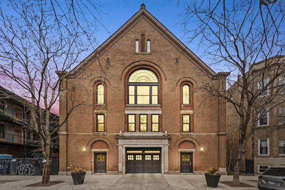 Front view of a brick building with large arched windows and a central entrance.