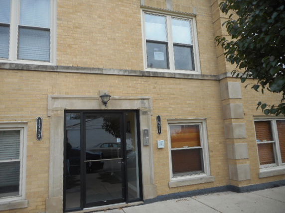 Front view of a brick building with multiple windows and a glass door entrance.