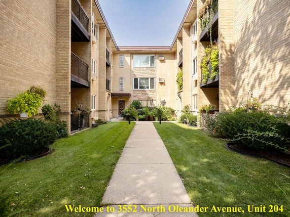 Front view of an apartment complex with multiple balconies and a pathway leading to the entrance.