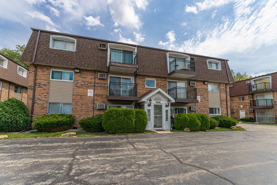 Front view of a multi-story apartment building with balconies and a central entrance.
