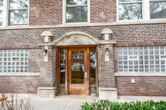 Front view of a brick building entrance with glass blocks and wooden door.