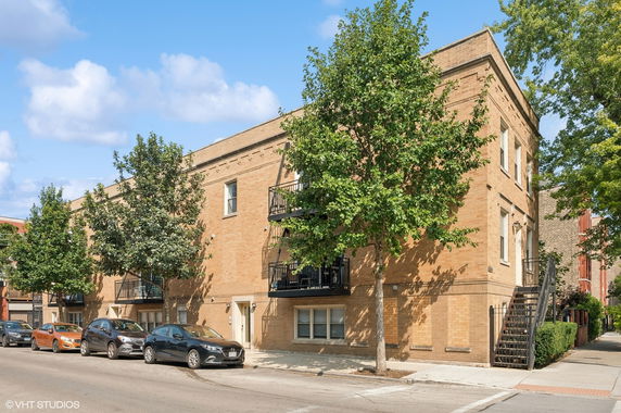 Front view of a two-story brick building with balconies and external staircase.