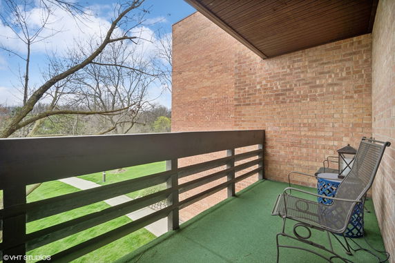 View from a balcony with brick walls and outdoor seating overlooking a green landscape.