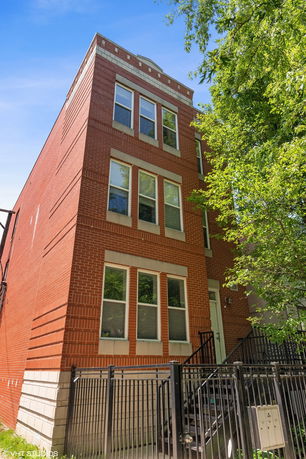 Front view of a three-story brick building with multiple windows and a gated entrance.