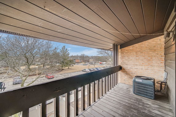 Balcony with a view of parking lot and trees from the building.