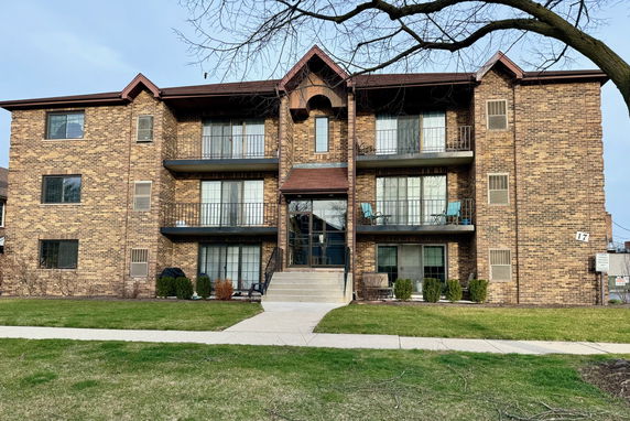 Front view of a multi-story brick apartment building with balconies.