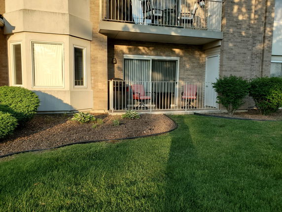 Front view of a building with a patio and sliding glass door on the ground floor.
