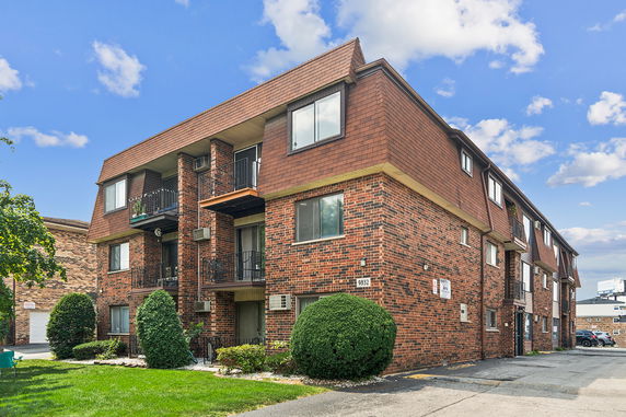 Front view of a multi-story brick apartment building with balconies and windows.