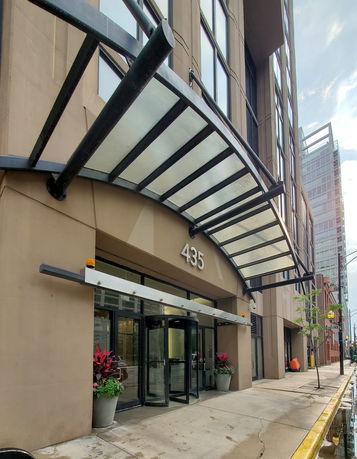 Front view of a multi-story building with a glass canopy and revolving door entrance.