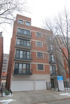 Front view of a multi-story brick apartment building with balconies.