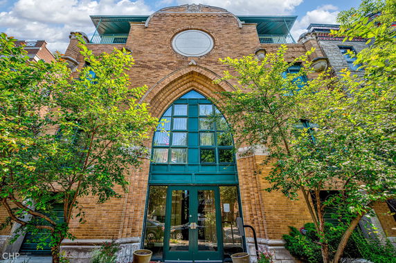 Front view of a multi-story building with arched windows and brick facade.