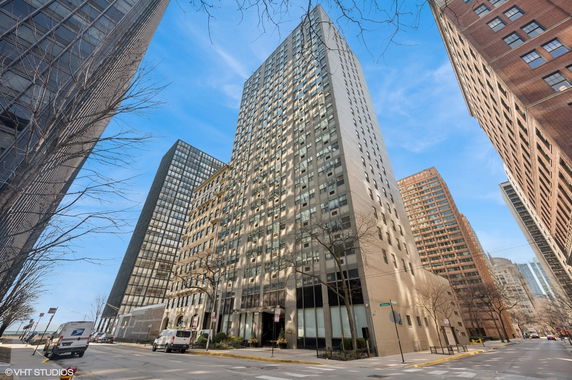 Front view of a tall city building surrounded by other skyscrapers.