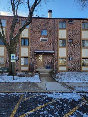 Front view of a multi-story brick building with multiple windows and an entrance door.