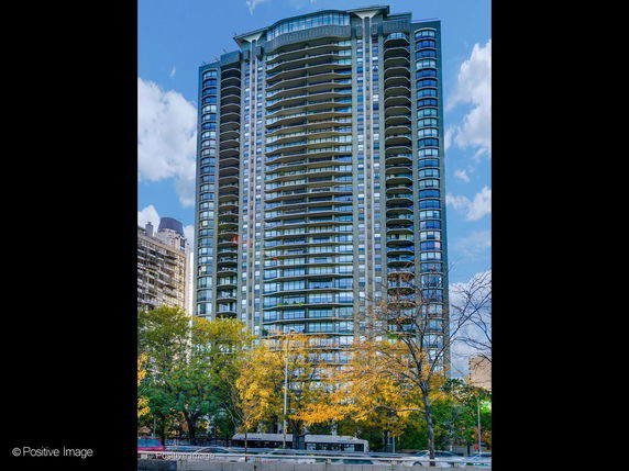 Front view of a tall residential building with multiple balconies.