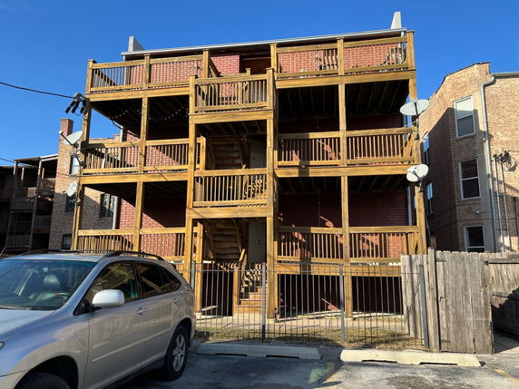 Front view of a multi-story building with wooden balconies and brick facade.