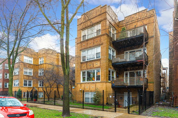 Front view of a multi-story brick apartment building with balconies.