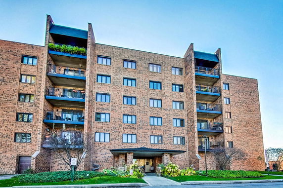 Front view of a multi-story brick apartment building with balconies.