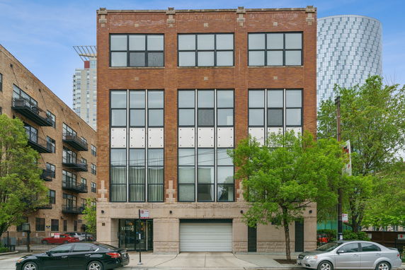 Front view of a multi-story brick building with large windows.