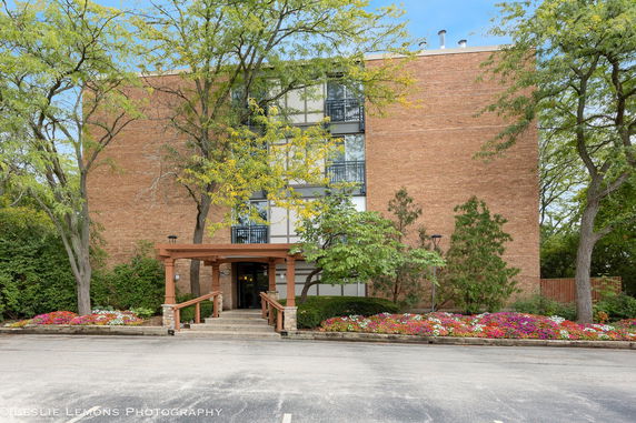 Front view of a multi-story brick building with a wooden entrance canopy.