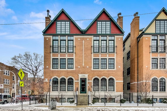 Front view of a multi-story brick building with large windows and gable roofs.