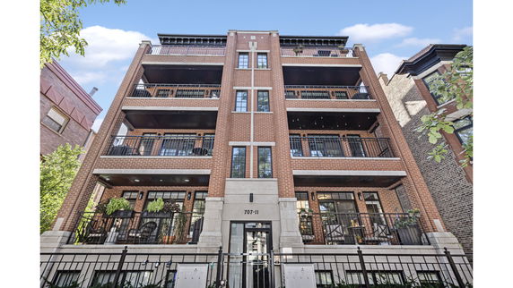Front view of a multi-story brick apartment building with balconies.
