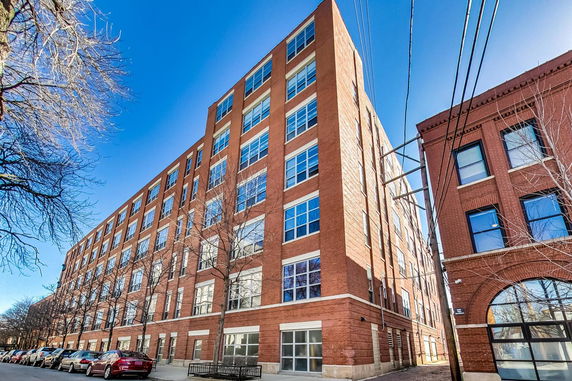 Front view of a multi-story brick building with large windows.