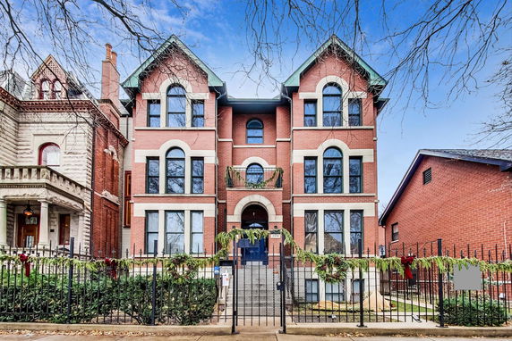 Front view of a multi-story brick building with arched windows and a decorative entrance.