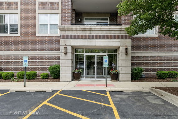 Front view of a brick building entrance with glass doors and reserved parking.
