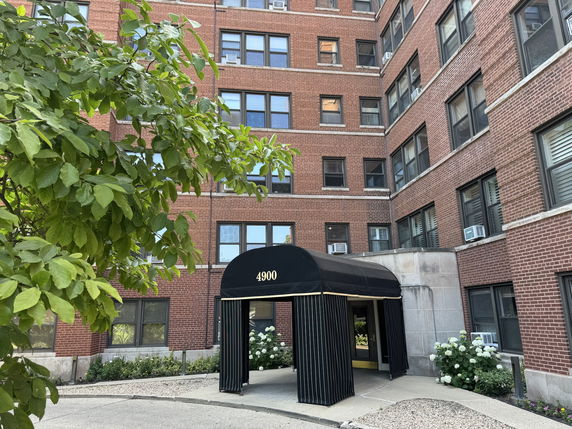 Front view of a multi-story brick building with an entrance canopy.
