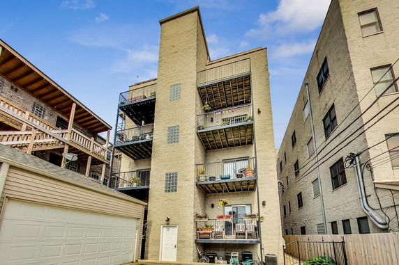 Rear view of a multi-story building with balconies and a garage door.