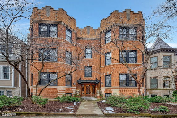 Front view of a multi-story brick building with decorative elements and multiple windows.